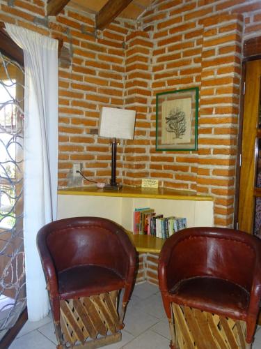 a room with two chairs and a desk and a brick wall at Villas Vista Suites Sayulita in Sayulita