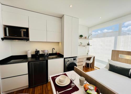 una cocina con armarios blancos y una mesa en una habitación en Apartaestudio en el Chico, en Bogotá
