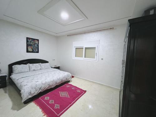 a bedroom with a bed and a red rug at Au dix sept in Dakhla