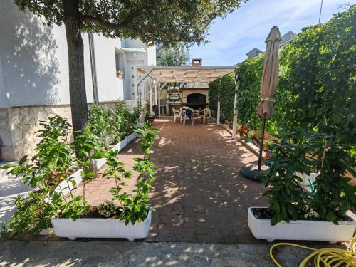 een patio met planten in potten en een parasol bij Maris apartments, Petrčane in Petrcane