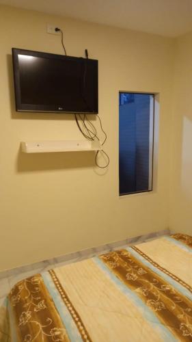 a bedroom with a flat screen tv on the wall at Hostal NOA El Valle in Quito