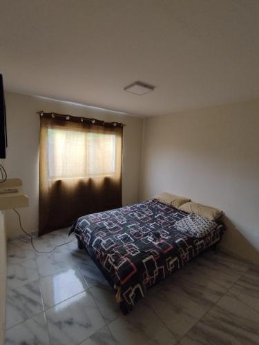 1 dormitorio con 1 cama en una habitación con ventana en Hostal NOA El Valle, en Quito