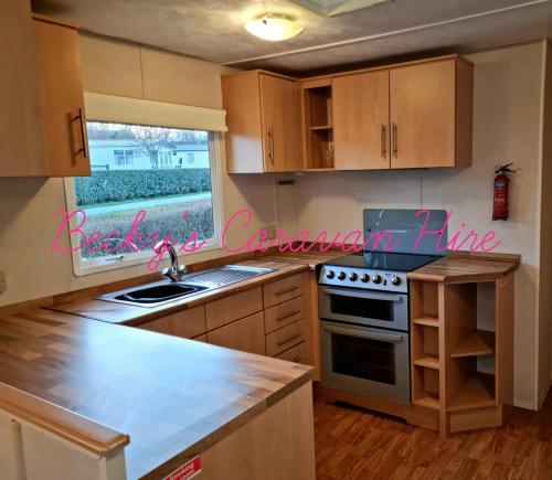 a kitchen with a sink and a stove top oven at Becky's Caravan at Marton Mere in Blackpool