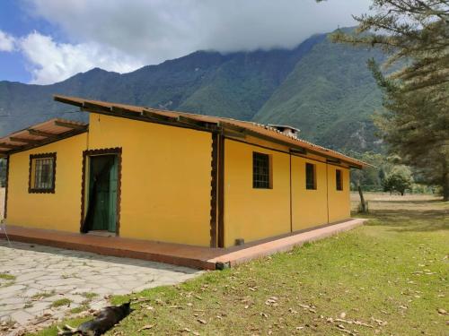 una casa amarilla con montañas en el fondo en Pululahua Magia y Encanto, en Quito