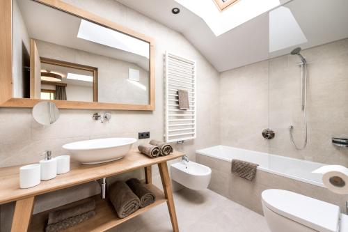 een badkamer met een wastafel, een toilet en een bad bij Hoferhof in Maranza