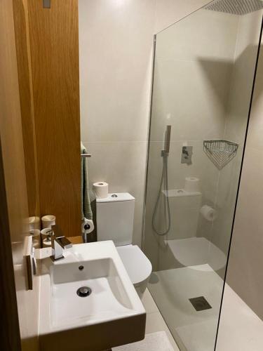 a white bathroom with a sink and a shower at Cabedelo Beach Loft in Darque