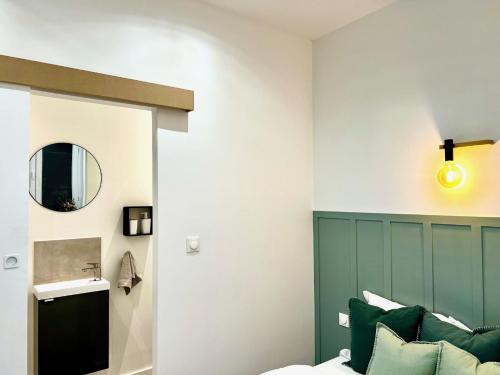 Schlafzimmer mit einem grünen Kopfteil und einem Spiegel in der Unterkunft MMGreenhouse - Fictus - Tourcoing in Tourcoing