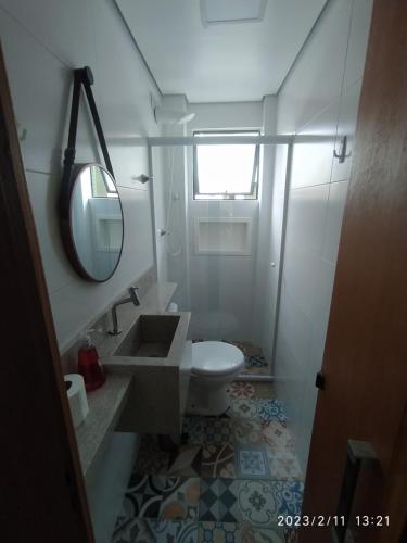 La salle de bains est pourvue de toilettes, d'un lavabo et d'un miroir. dans l'établissement Kitpraiana Ocean, à Praia Grande