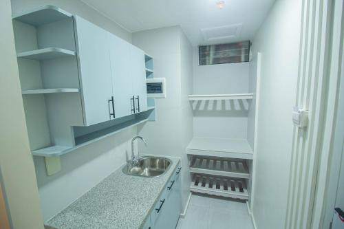 a white kitchen with a sink and shelves at Twin Hearts Residences 1 in Roxas City