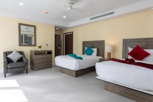1 dormitorio con 2 camas y 1 silla en The New View Inn en Tortola Island