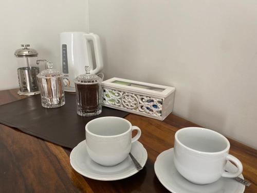 twee kopjes en schotels op een tafel met een koffiezetapparaat bij Gomez Point Mendoza in Mendoza