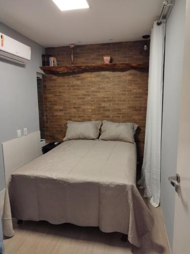 1 dormitorio con 1 cama grande y pared de ladrillo en Residencial Letícia Miranda en Aracajú