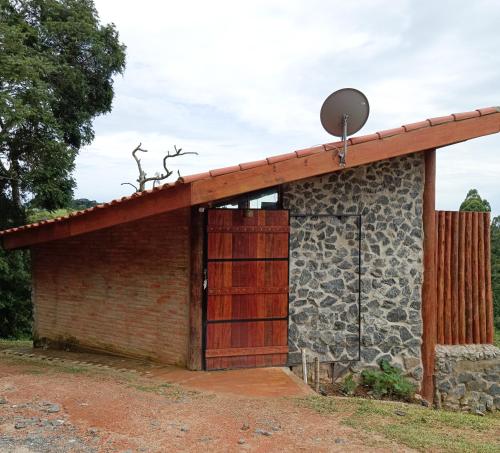 a building with a wooden door and a stone wall at Tiny Houses O Olival - aluguel temporada in Cunha