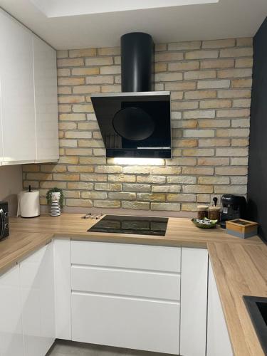 a kitchen with white cabinets and a brick wall at Apartments Sleep & GO Modlin Airport in Nowy Dwór Mazowiecki