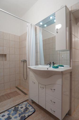 a bathroom with a sink and a shower and a mirror at Lia Apartman Pécs in Pécs