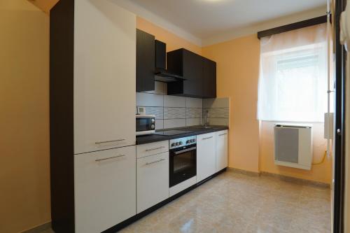una cucina con armadietti bianchi ed elettrodomestici neri di Lia Apartman Pécs a Pécs