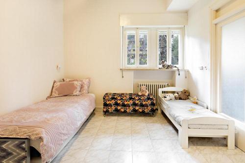 Cette chambre comprend deux lits, un canapé et une fenêtre. dans l'établissement Rechavia Apartment, à Jérusalem