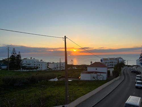 una puesta de sol sobre una carretera con el océano y edificios en Apartment Ericeira South, en Ericeira