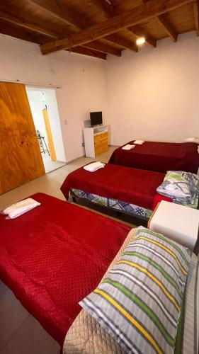 Habitación con 3 camas y sábanas rojas. en Las Moras en Mendoza