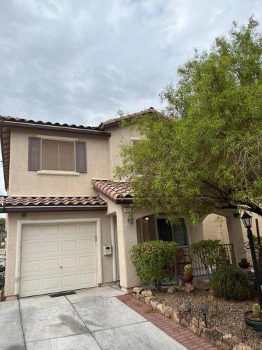a house with a garage and a tree in front of it at Vic's 3 bedroom 4beds & POOL centrally located! in Las Vegas