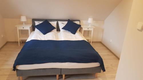 a bed with blue and white sheets and blue pillows at Pueblo Apartamenty in Stegna