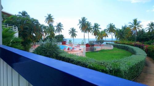 uma vista para um resort com uma piscina e palmeiras em Bord de mer - Studio Papiyon em Le Gosier