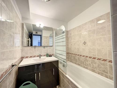 ein Badezimmer mit einem Waschbecken, einer Badewanne und einem Spiegel in der Unterkunft Spacieux T2 tout confort in Tarbes