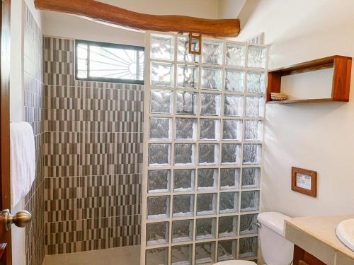 uma casa de banho com um chuveiro e uma parede com um bloco de vidro. em Mar Adentro Sanctuary em Tola