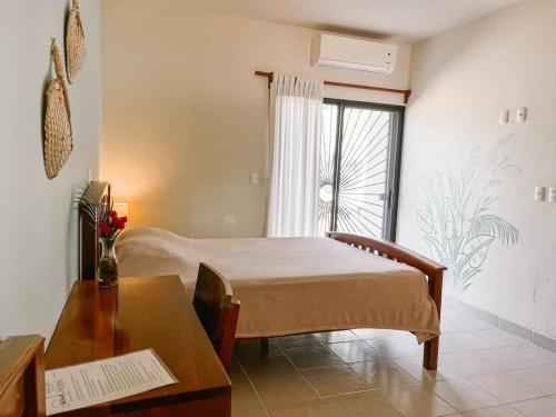 a bedroom with a bed and a table and a window at Mar Adentro Sanctuary in Tola