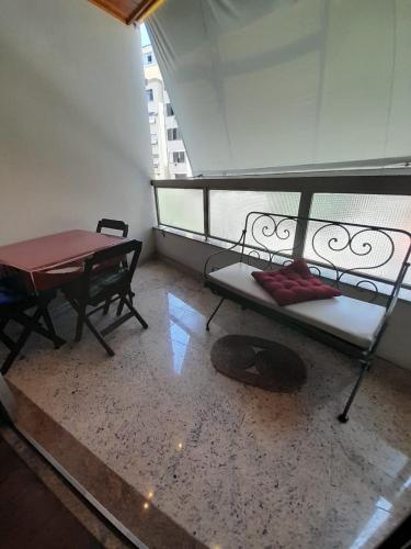 Habitación con cama y mesa en el balcón. en Lindo apartamento com 2 suites, en Río de Janeiro