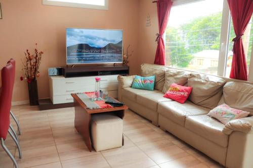 sala de estar con sofá y TV en Dptos Aloha en Ushuaia