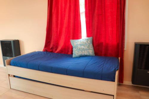 a bed in front of a window with red curtains at Dptos Aloha in Ushuaia