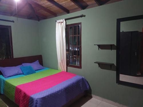 um quarto com uma cama colorida e uma janela em Finca La Luisa en Rozo - cerca a Cali em Rozo