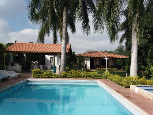 uma piscina em frente a uma casa com palmeiras em Finca La Luisa en Rozo - cerca a Cali em Rozo