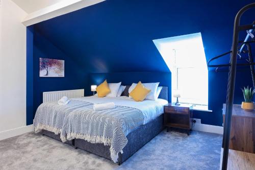 a blue bedroom with a bed with yellow pillows at The Stanley Spacious Modern Home Near the Beach perfect for a family holiday or Contractor stay in Blythe