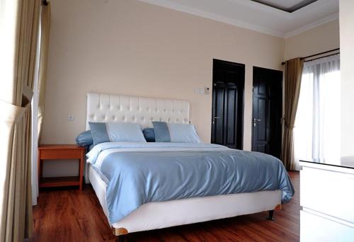 a bedroom with a large bed with blue sheets and a window at Blue Villa in Balikpapan