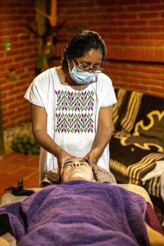 a woman in a mask cutting a mans head at Huayápam Yù'ú Lodge in San Andrés Huayapan