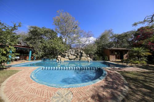 a swimming pool in a yard with a rock wall at Huayápam Yù'ú Lodge in San Andrés Huayapan