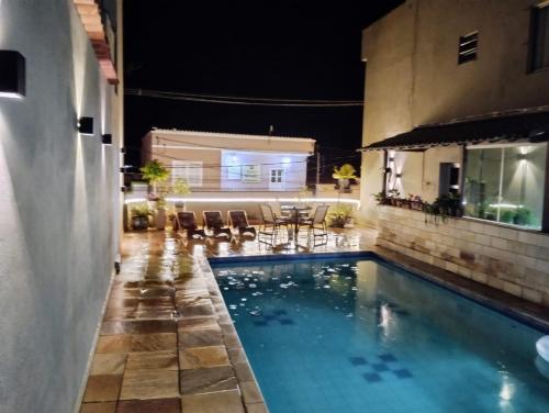 a swimming pool in a backyard at night at Hotel de Minas in Caxambu