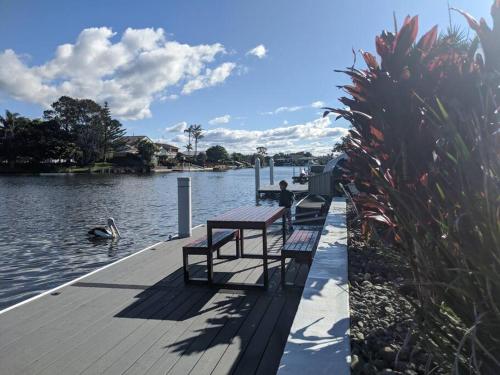 a row of benches sitting on a dock next to the water at Grand Riviera Forster- waterfront, pool, wharf in Forster