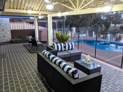 a patio with couches and a table and a pool at Grand Riviera Forster- waterfront, pool, wharf in Forster