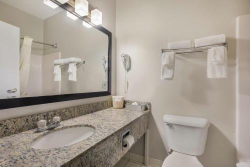a bathroom with a toilet and a sink and a mirror at MainStay Suites Joliet I-55 in Joliet