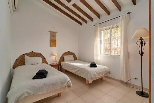 a bedroom with two beds and a window at Casa Rural Boas, con vistas impresionantes, Barbacoa en Cómpeta by CostaDelSolEscapes in Cómpeta