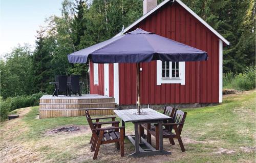 a picnic table with an umbrella in front of a red shed at Lovely Home In Råda With House Sea View in Råda