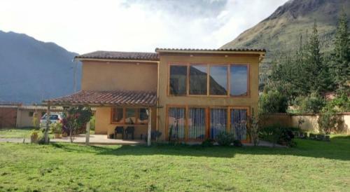 a house in a field with a mountain in the background at Casafranca in Ollantaytambo