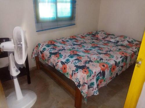a bedroom with a bed with a floral comforter and a fan at ¡VILLA AZUL! LUGAR ENCANTADOR A 60 METROS DEL MAR :o ;) in Necoclí