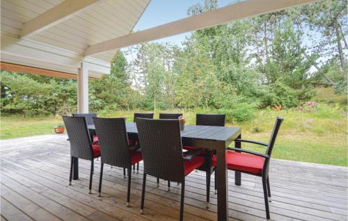 a wooden table and chairs on a deck with a porch at Holiday Home Vestervej Rømø Ix in Rømø