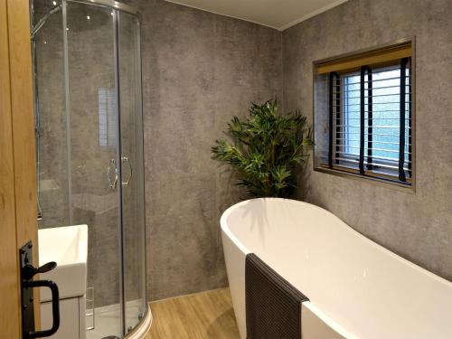 uma casa de banho com uma banheira e um chuveiro em vidro. em Terraughtie Cottage East-uk31767 em Terreglestown