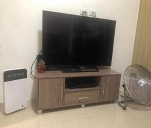 een flatscreen-tv op een houten entertainmentcentrum bij Shore Residences in Manilla