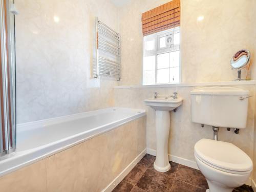 a bathroom with a toilet and a tub and a sink at Hafod in Llanengan